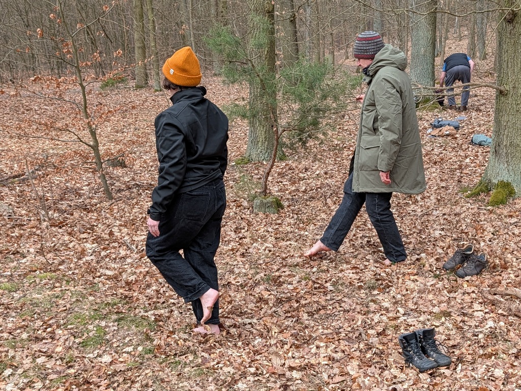 Zwei Menschen schleichen barfuss durch den Wald.
