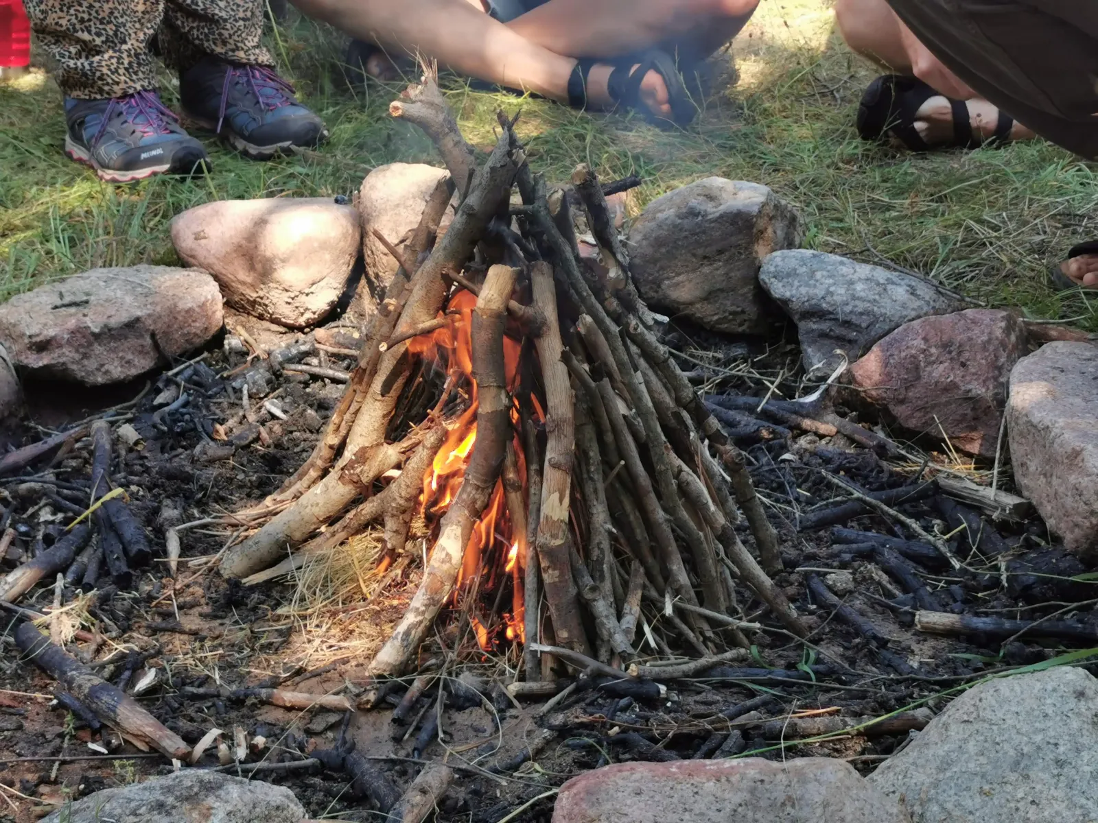 Ein kleines Tipi Feuer brennt in einer Feuerstelle beim Familientag.