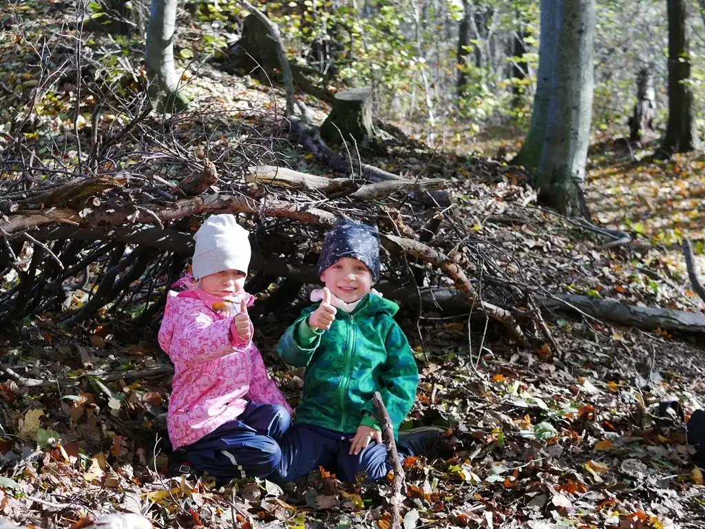 Zwei Kinder zeigen den Daumen hoch und haben Spaß beim Familientag im Wald.