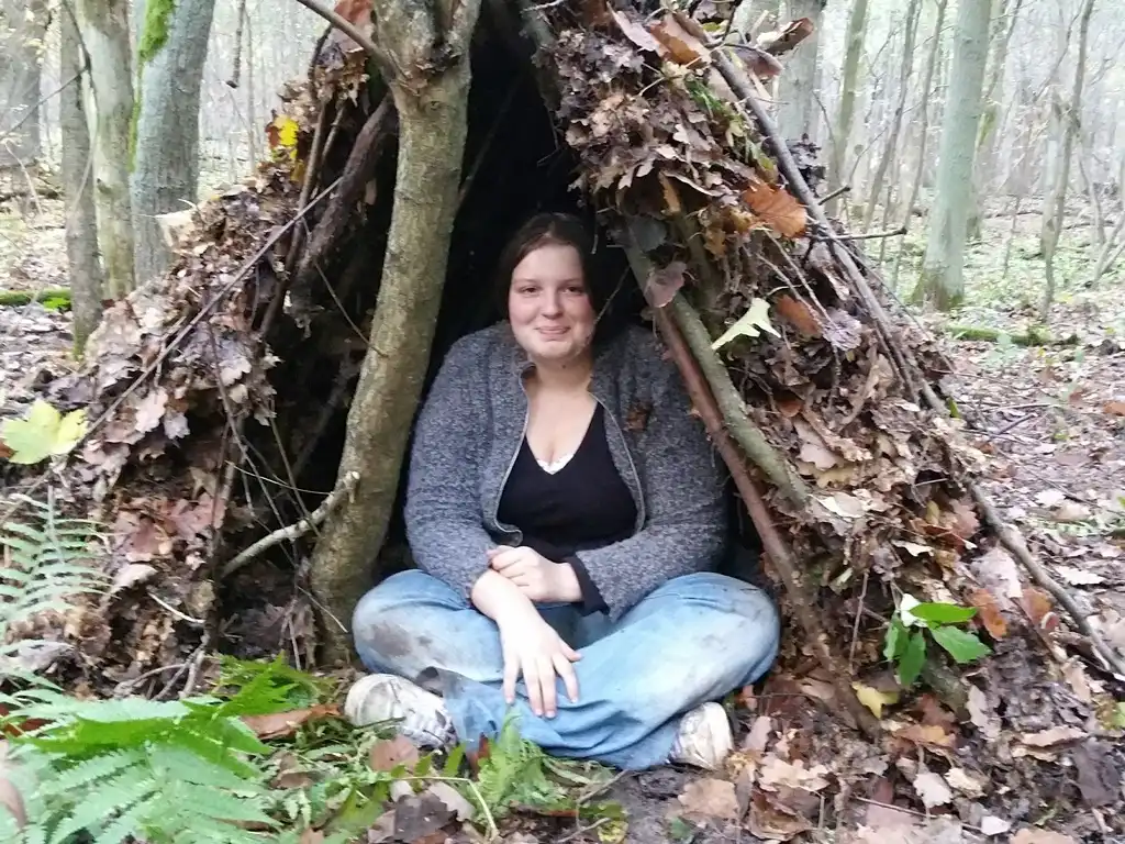 Ein Teenager sitzt in ihrer selbstgebauten Laubhütte.