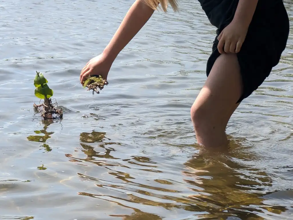 Ein Kind lässt beim Feriencamp ein Naturboot zu Wasser.