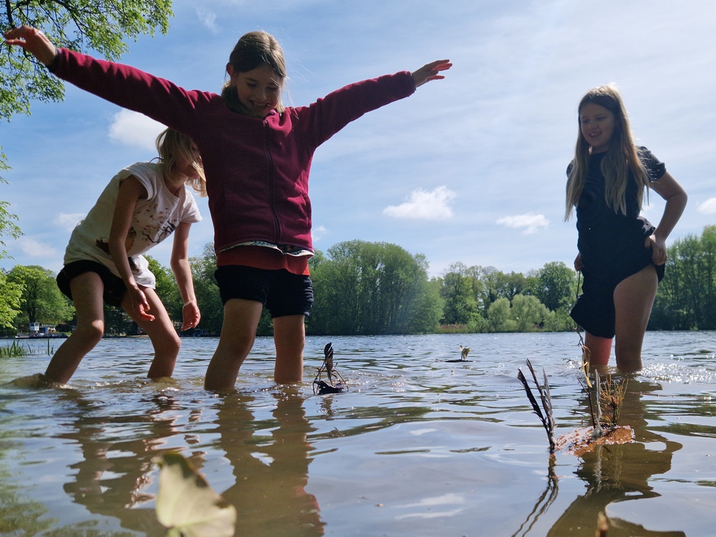 Drei Kinder setzen ihre selbstgebauten Miniflösse ins Wasser.