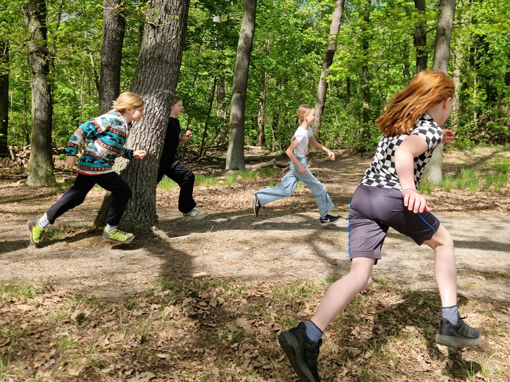 Kinder rennen auf einer Schatzsuche durch den Wald.