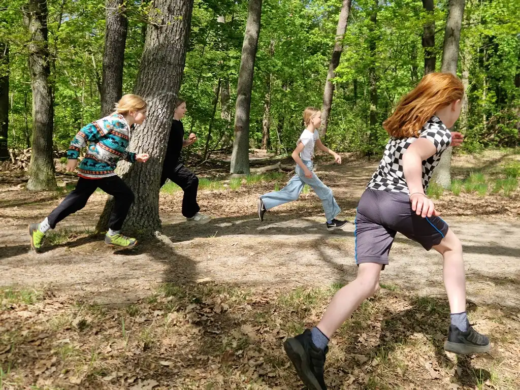 Kinder rennen auf einer Schatzsuche durch den Wald.