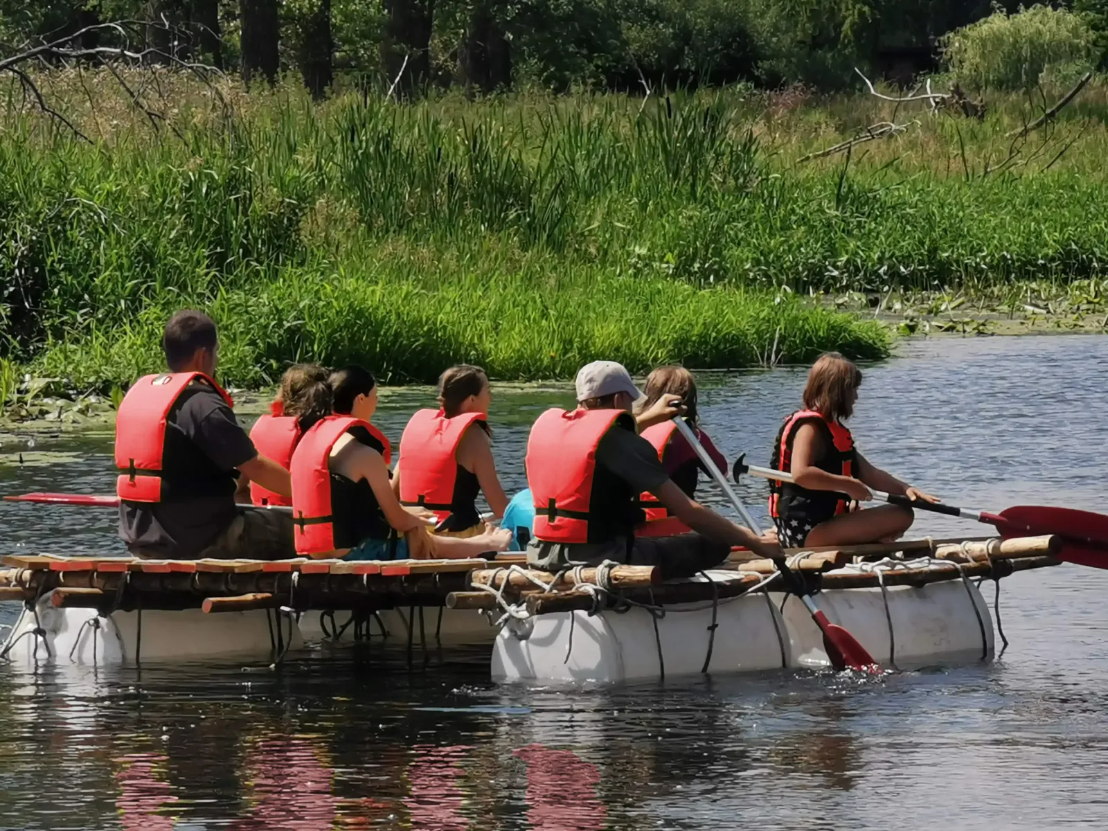 Eine Klasse testet ihr selbstgebautes Floß auf dem Wasser.