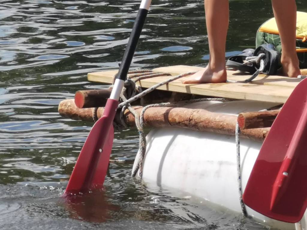 Ein Kind paddelt auf einem Floß auf dem Wasser.